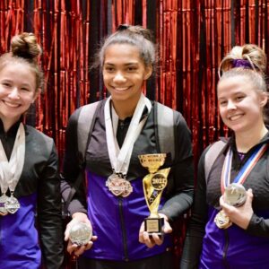 Gymnasts celebrating winning a trophy in competitve gymnastics.