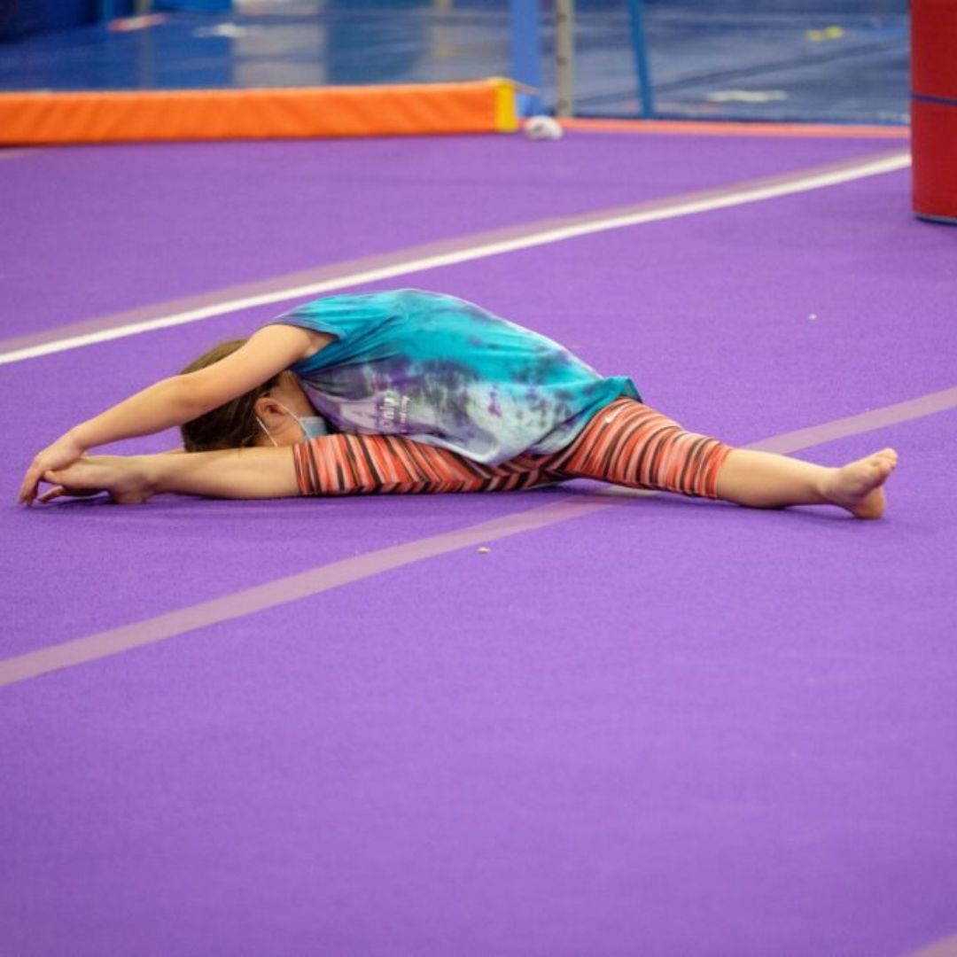 gymnast stretching legs on floor