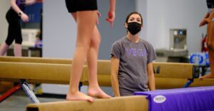 gymnastics student on balance beam with coach watching